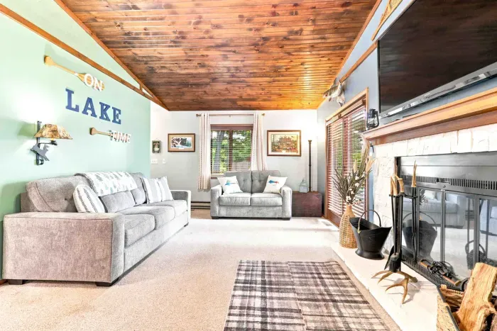 Unwind in this warm, rustic living space featuring vaulted wood ceilings and cozy seating. Unplug and relax by the stone fireplace or gather for movie nights around the flat-screen TV in a classic cabin setting built for comfort.