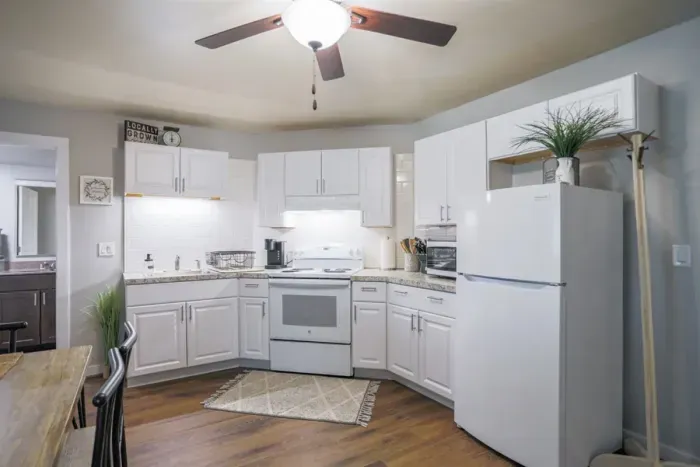 A modern kitchen equipped with high-end appliances and ample lighting. It has a coffee maker, oven, stove top, utensils, and all it takes to fix a delicious meal.