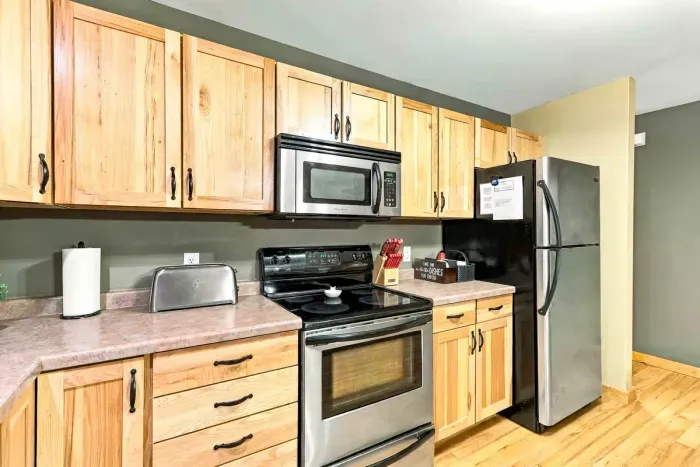 Fully equipped for all your culinary needs, this kitchen features natural wood cabinetry, generous counter space, and stainless steel appliances. Complete with a toaster, knife block, microwave, stove, and full-size refrigerator, meal prep is a breeze.