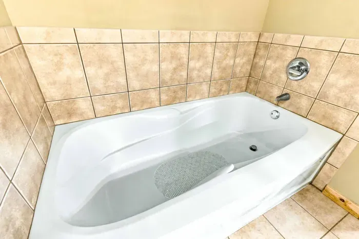 Treat yourself to a spa-like retreat in this spacious main bathroom. Features include a deep soaking bathtub surrounded by classic neutral tile and a separate glass-enclosed walk-in shower for ultimate comfort and convenience.