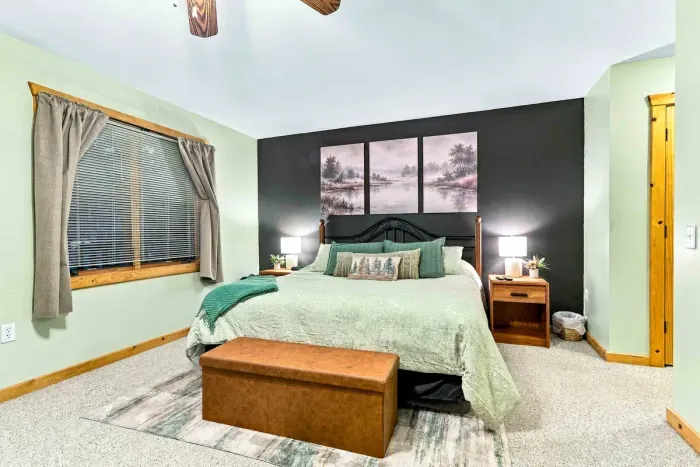 Unwind in style! Cozy up with plush pillows, soft sage bedding, and tranquil lakeside wall artwork.