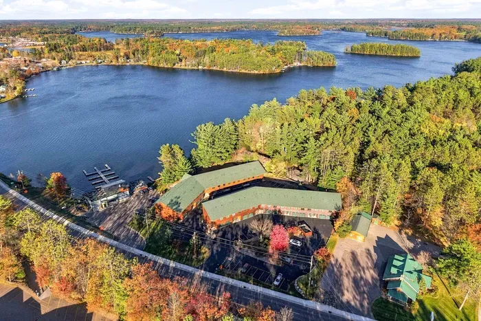 Arrival is a breeze at this mountain-lakeside lodge! Featuring an expansive paved parking lot with clearly numbered spaces, multiple garage bays, and easy access to private ground-level entrances. Framed by evergreen trees and warm wood log siding.