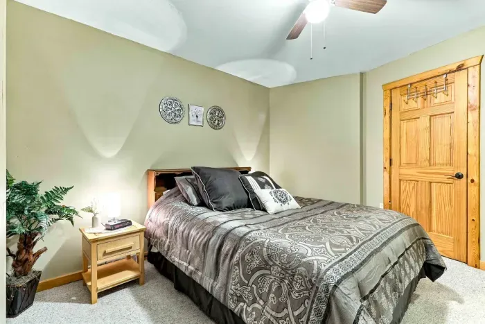 Soothing sage walls and patterned charcoal linens create an inviting, stylish ambiance. Enjoy modern conveniences including dual bedside tables with lamps, a digital clock, and ceiling fan cooling.