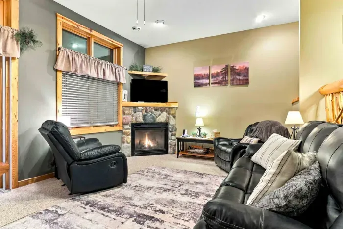 Designed for complete relaxation, this spacious lower-level sitting area features a plush leather sofa, oversized recliners, and a patterned area rug over soft carpet. Unwind beside the warm corner stone fireplace and TV after a day out on the lake.