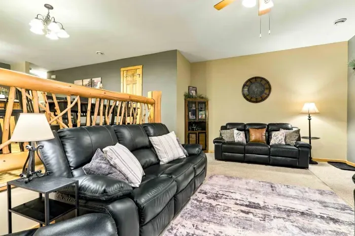 Sink into plush leather seating with throw pillows and blankets in this cozy nook. Natural light filters through large wood-trimmed windows, while the stone fireplace adds a touch of classic lodge charm.