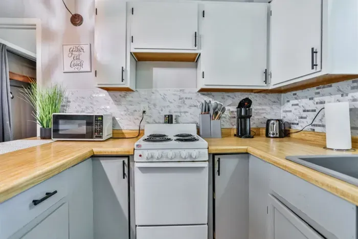 A modern kitchen equipped with high-end appliances and ample lighting. It has a coffee maker, oven, stove top, utensils, and all it takes to fix a delicious meal.