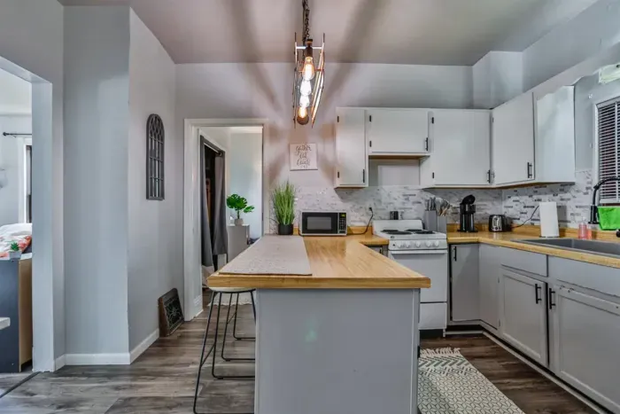 A modern kitchen equipped with high-end appliances and ample lighting. It has a coffee maker, oven, stove top, utensils, and all it takes to fix a delicious meal.