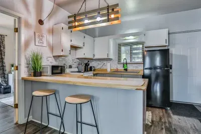 A modern kitchen equipped with high-end appliances and ample lighting. It has a coffee maker, oven, stove top, utensils, and all it takes to fix a delicious meal.