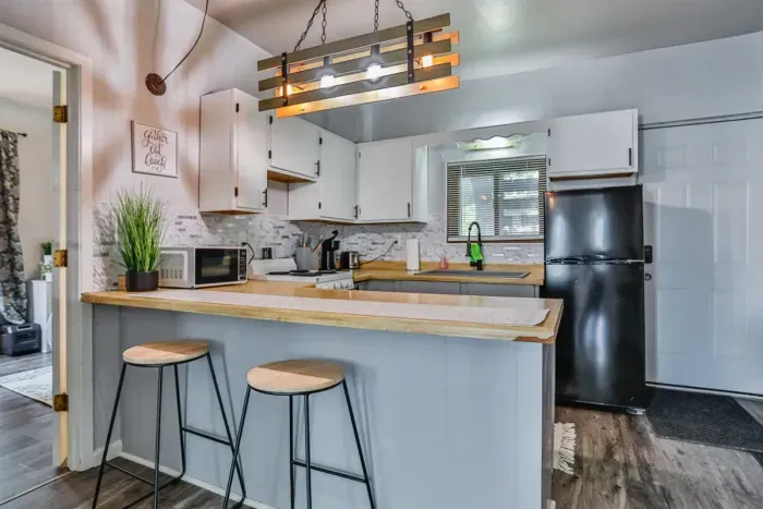 A modern kitchen equipped with high-end appliances and ample lighting. It has a coffee maker, oven, stove top, utensils, and all it takes to fix a delicious meal.