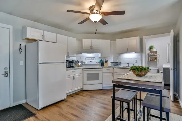 A modern kitchen equipped with high-end appliances and ample lighting. It has a coffee maker, oven, stove top, utensils, and all it takes to fix a delicious meal.