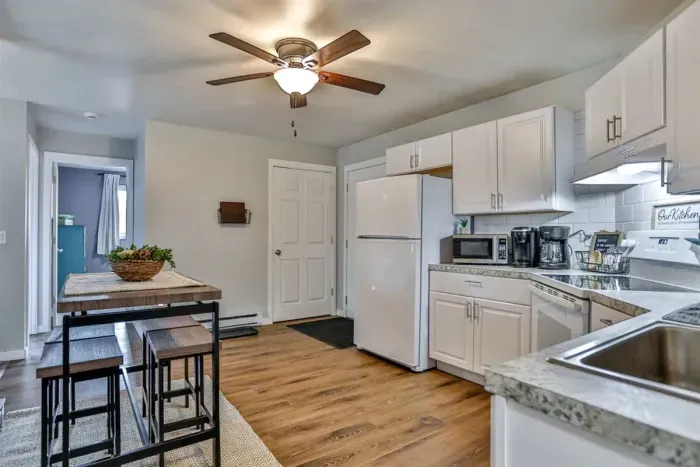 A modern kitchen equipped with high-end appliances and ample lighting. It has a coffee maker, oven, stove top, utensils, and all it takes to fix a delicious meal.