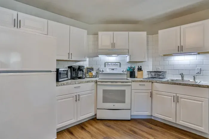 A modern kitchen equipped with high-end appliances and ample lighting. It has a coffee maker, oven, stove top, utensils, and all it takes to fix a delicious meal.
