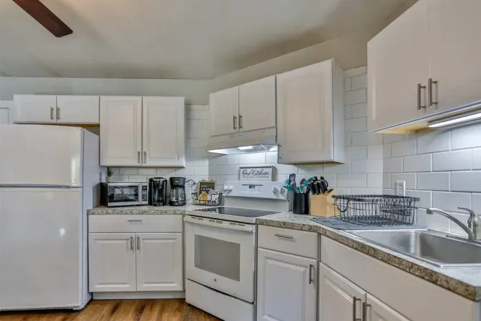 A modern kitchen equipped with high-end appliances and ample lighting. It has a coffee maker, oven, stove top, utensils, and all it takes to fix a delicious meal.