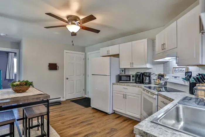 A modern kitchen equipped with high-end appliances and ample lighting. It has a coffee maker, oven, stove top, utensils, and all it takes to fix a delicious meal.
