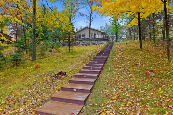 Nestled among mature trees, this home is set on a beautiful hillside with scenic views in every season. The illuminated stairway provides easy access while adding a touch of charm and character to the landscape.