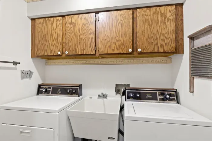 Dedicated laundry space featuring a warm wooden overhead cabinet