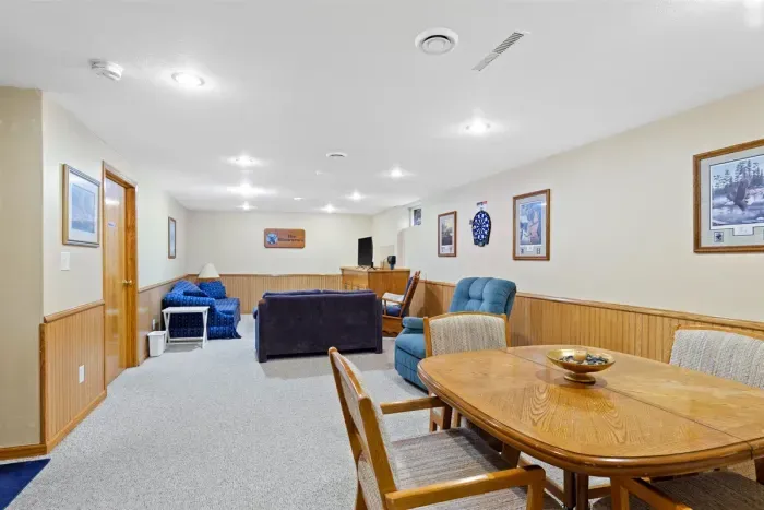 Spacious and comfortable lower-level lounge featuring cozy seating, a dining area, and soft lighting, perfect for relaxing after a day of exploring. Ideal for families or groups to gather, unwind, or enjoy a game night.