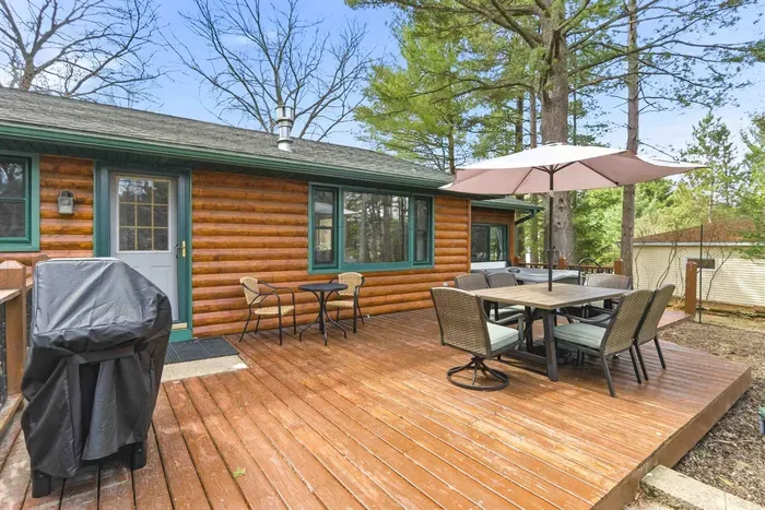Private wooded backyard deck with outdoor dining set and umbrella, perfect for relaxing stays.