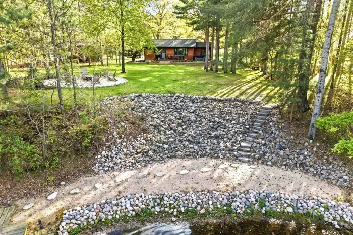 Step from the cabin to the shoreline and enjoy easy days by the water, with a sandy beach, wooded privacy, and a peaceful firepit setting just beyond.