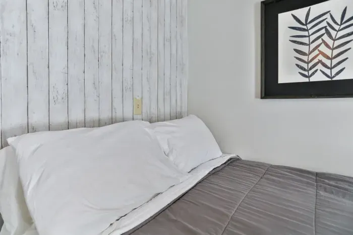A close-up view of a neatly made bed with white pillows and a gray comforter.