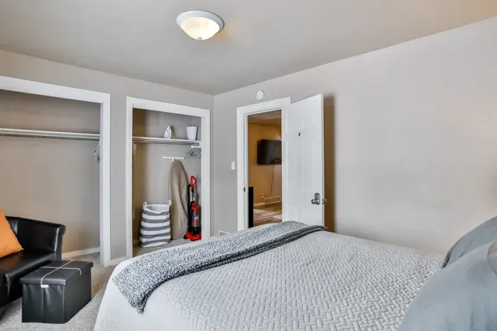 Comfortable bedroom with cozy bedding, open closets for easy storage, and a clean, functional layout designed for a relaxing stay.
