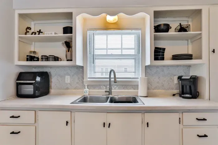 Stylish kitchen sink space featuring open shelving, modern fixtures, and a bright, clean design.
