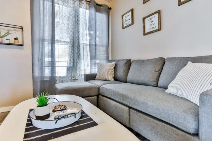Cozy seating nook with a plush gray sectional, soft throw pillows, and natural light streaming through sheer curtains.