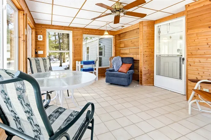 Sun-filled and inviting, this wood-paneled sunroom features comfy seating and a dining table, perfect for relaxing or enjoying the view.