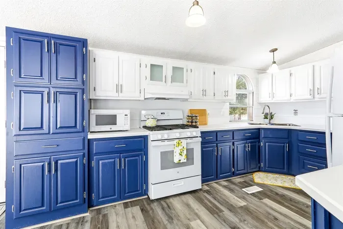 Bright kitchen with stylish blue base cabinets and white wall cabinets, perfect for all your cooking needs.
