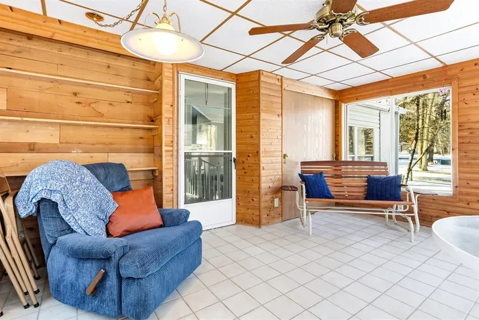 Relax in this bright, inviting sunroom with warm wood-paneled walls and large windows that fill the space with natural light.