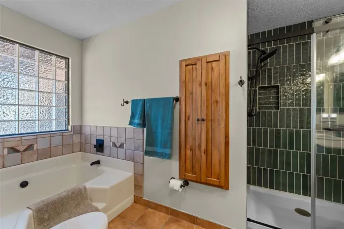 Relax in a bright, private bathroom with a large soaking tub, separate walk-in shower, plush towels, and stylish wooden storage.