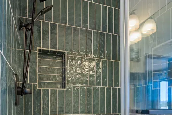 Enjoy a sleek walk-in shower featuring beautiful green tile, modern black fixtures, and a clean, spa-like feel.