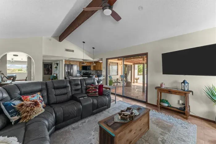 Unwind in a stylish living room with a large flat-screen TV, comfortable leather seating, and high vaulted ceilings that make the space feel open and airy.
