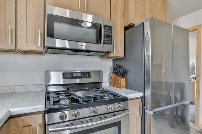 Modern kitchen with sleek design, stove, fridge, and dining space.