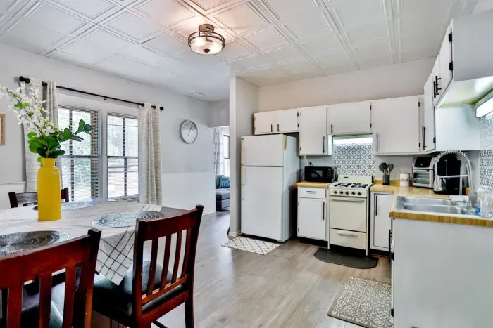 A modern kitchen equipped with high-end appliances and ample lighting. It has a coffee maker, oven, stove top, utensils, and all it takes to fix a delicious meal.