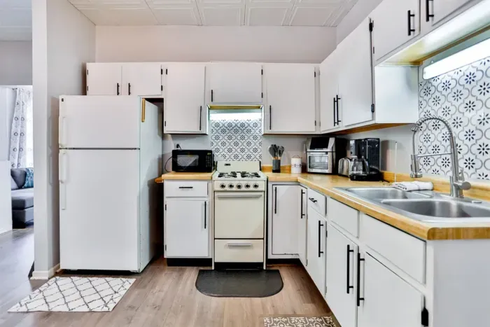 A modern kitchen equipped with high-end appliances and ample lighting. It has a coffee maker, oven, stove top, utensils, and all it takes to fix a delicious meal.