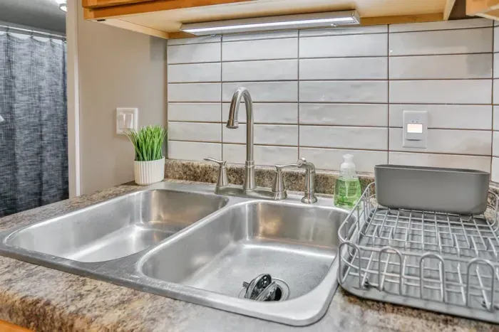 Fully equipped and modern—our kitchen includes essential electronics and utensils, featuring a stainless steel refrigerator, stove, coffee maker, and a full set of cookware and tableware
