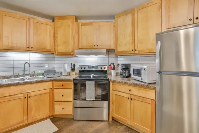 Modern and efficient—everything you need to create a delicious meal. The kitchen features a stainless steel refrigerator, stove, coffee maker, kitchenette oven, kettle, and blender.