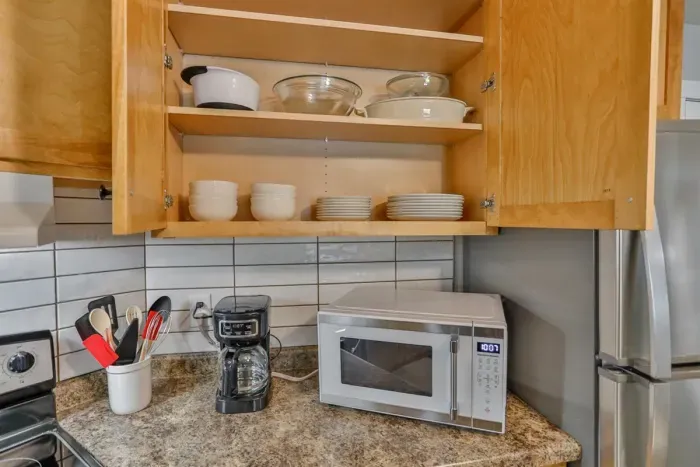 Fully equipped and modern—our kitchen includes essential electronics and utensils, featuring a stainless steel refrigerator, stove, coffee maker, and a full set of cookware and tableware