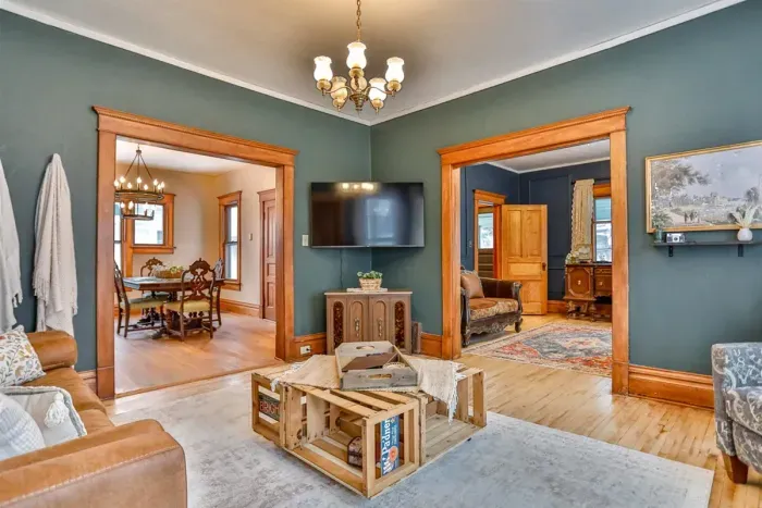 Warm, vintage-inspired living space with rich green walls, original wood trim, and cozy furnishings.