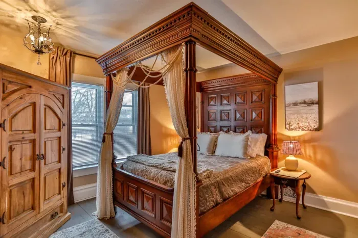 Elegant and cozy bedroom featuring a stunning four-poster canopy bed, warm wood furnishings, and soft ambient lighting.