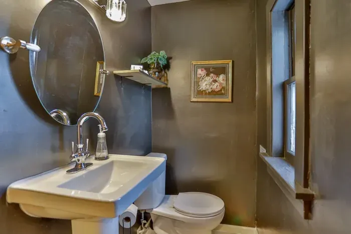 A clean and functional half bathroom with a pedestal sink, modern fixtures, and a window for natural light and ventilation, ideal for guest convenience.