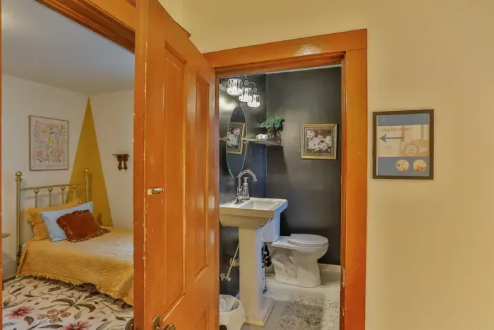 A clean and functional half bathroom with a pedestal sink, modern fixtures, and a window for natural light and ventilation, ideal for guest convenience.