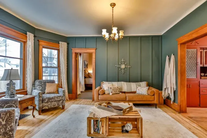 Warm, vintage-inspired living space with rich green walls, original wood trim, and cozy furnishings.