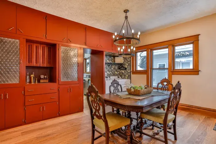 Warm and inviting dining space with vintage charm, featuring rich wood floors, a classic dining table, statement chandelier, and beautiful built-in cabinetry.