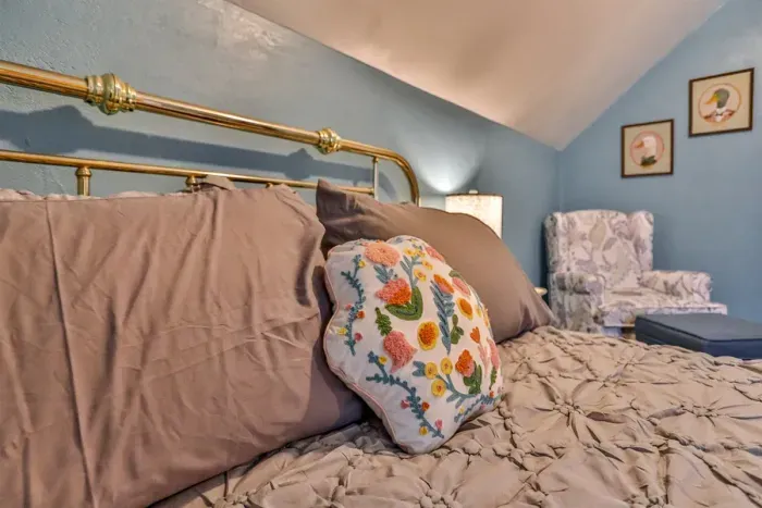 Charming bed, plush linens, and warm ambient lighting.