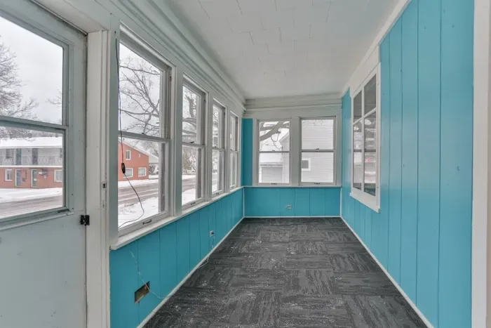 A bright enclosed porch that offers a versatile space to relax and enjoy the neighborhood views.