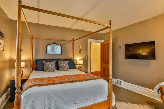 Charming, serene bedroom featuring a classic four-poster bed, plush linens, and warm ambient lighting.