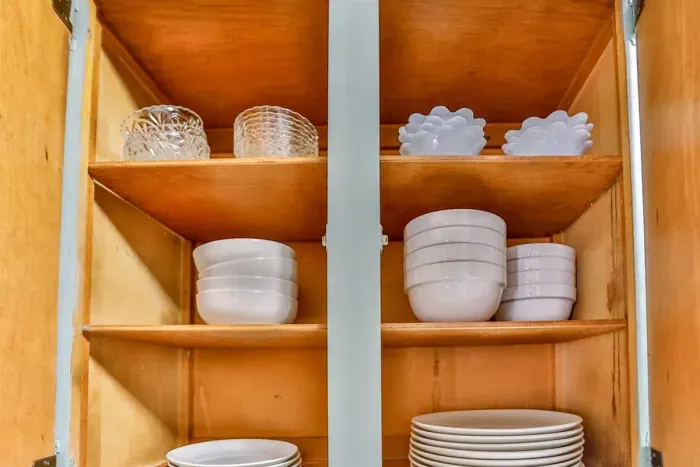 We prioritize your convenience with a well-equipped kitchen. The pantry is stocked with sets of clean white ceramic bowls and plates to meet all your dining needs.