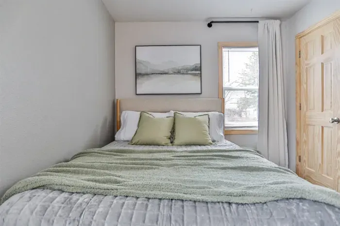 Spacious bedroom with soft pillows, cool air, and a calm, inviting setting.